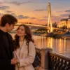 Молодая пара на набережной Туры в Тюмени на фоне подсвеченного моста Влюбленных и драмтеатра
