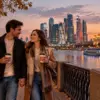 Тёплая осенняя прогулка пары с кофе по набережной Москвы-реки на фоне вечерних огней Москва-Сити
